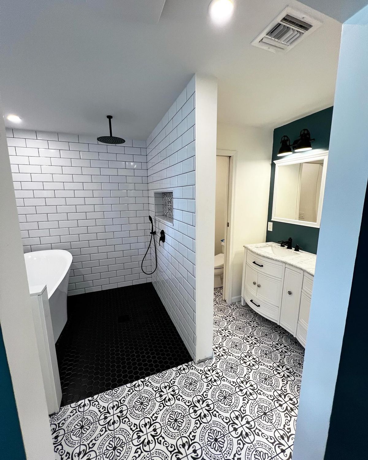Black and white bathroom with subway tile shower and patterned floor tile